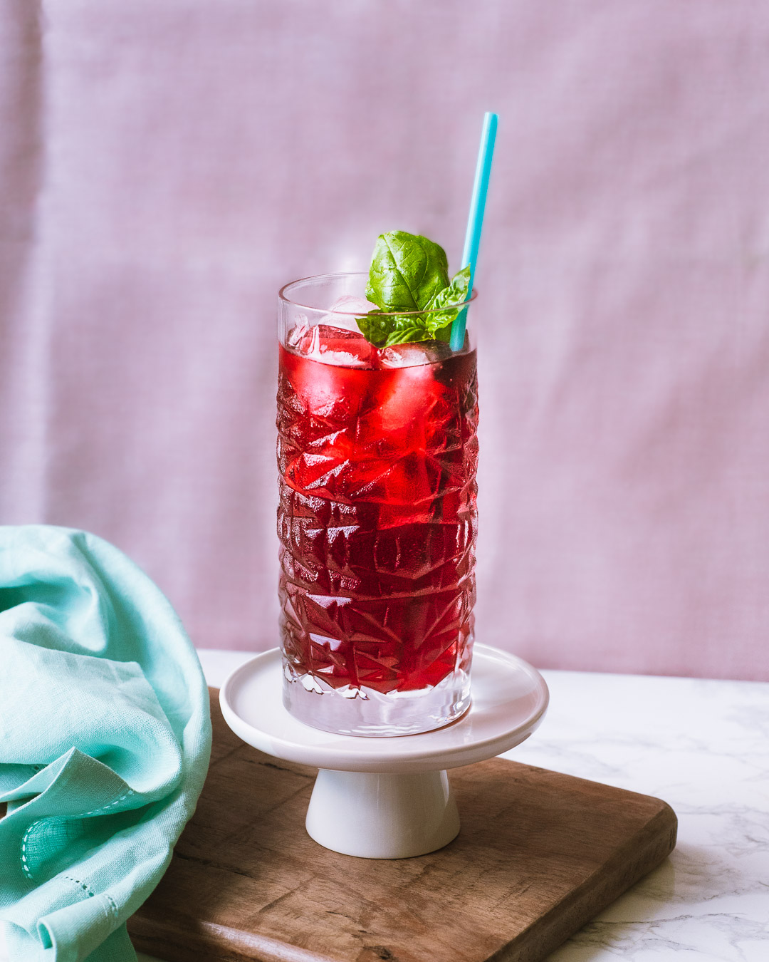 Tall glass with red iced tea and a basil garnish