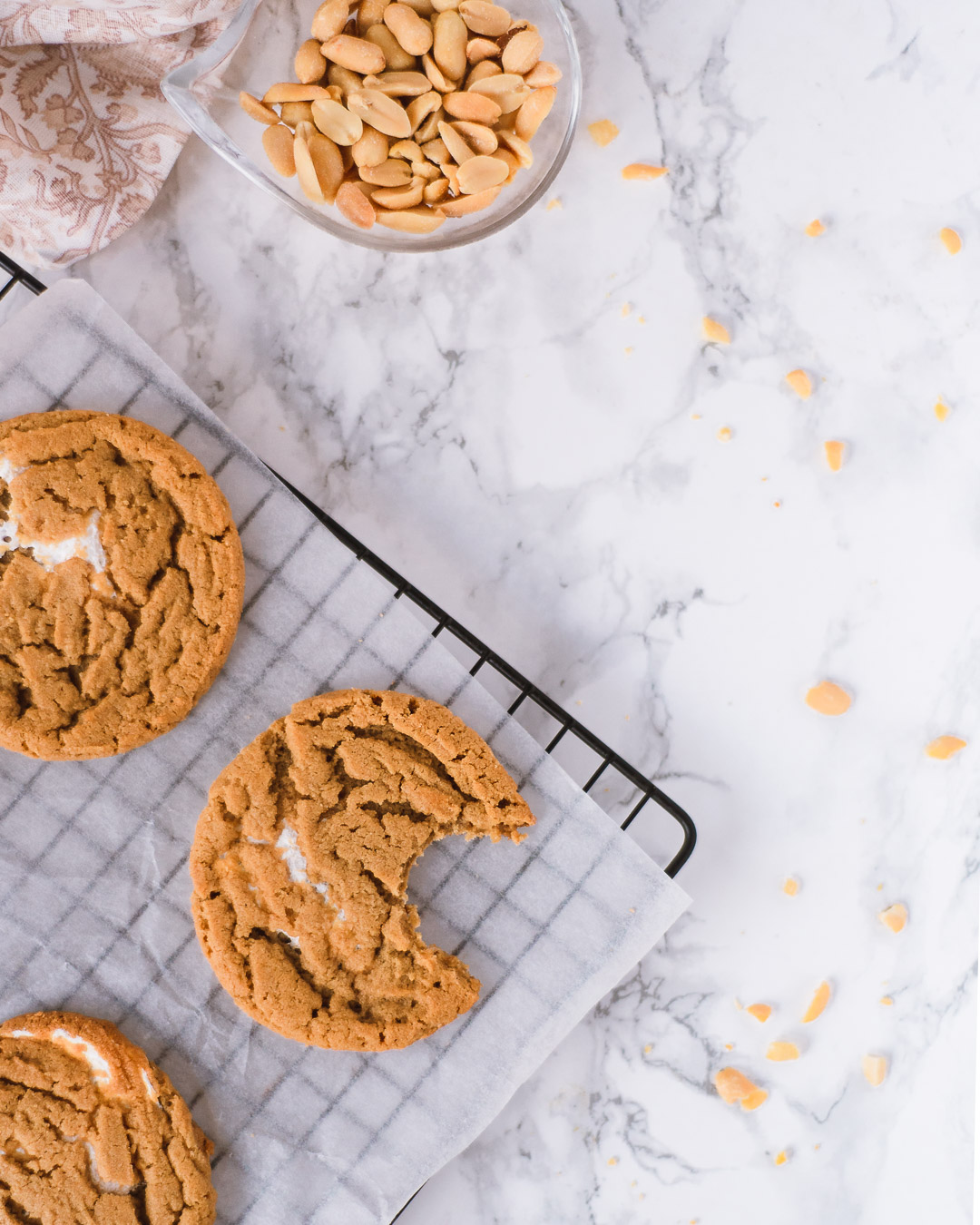 Peanut butter cookies on a wire rack with a small bowl of peanuts